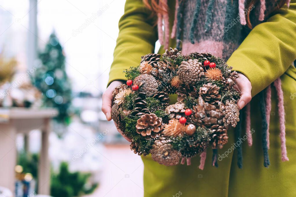 The girl holds in her hands New Year's, Christmas wreath of decorative ornaments for the home. Against the background of a veteran workshop
