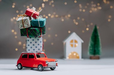 Çatıda hediyeler olan kırmızı bir araba. Evin arka planına ve ağaca karşı. Noel ve Yeni Yıl teması kavramı