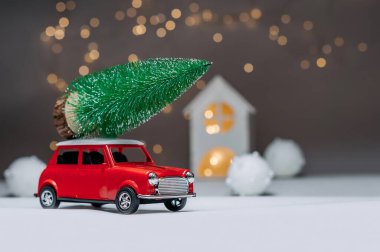 Çatıda Noel ağacı olan kırmızı bir araba. Evin arka planına karşı. Noel ve Yeni Yıl teması kavramı