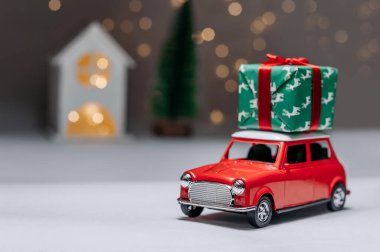 Ormanın arka planında kırmızı bir araba ve bir ev yılbaşı hediyeleri getirecek.