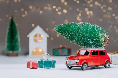 Çatıda Noel ağacı olan kırmızı bir araba. Evin arka planına karşı. Noel ve Yeni Yıl teması kavramı