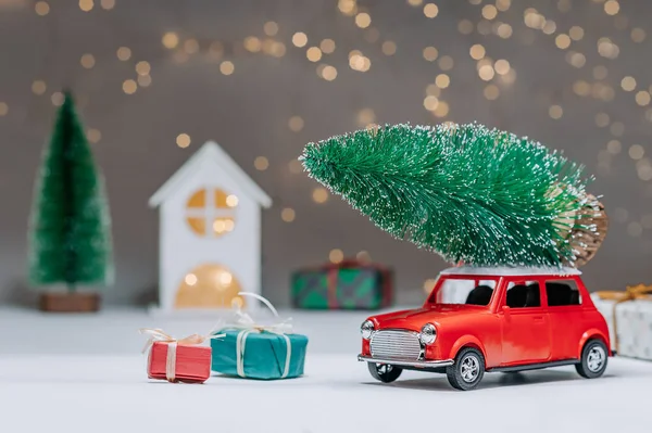 Çatıda Noel ağacı olan kırmızı bir araba. Evin arka planına karşı. Noel ve Yeni Yıl teması kavramı