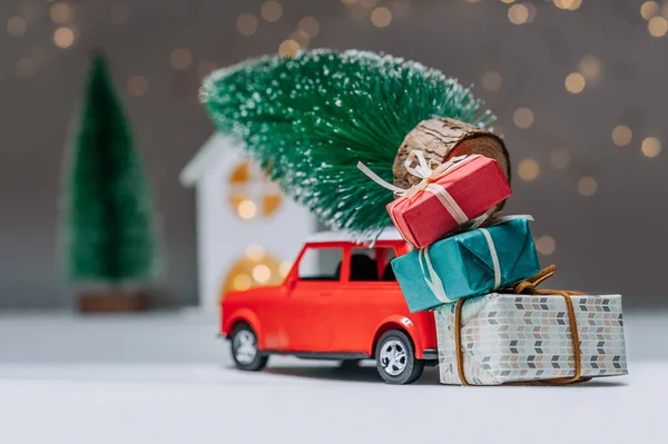 Çatıda Noel ağacı olan kırmızı bir araba. Evin arka planına karşı. Noel ve Yeni Yıl teması kavramı
