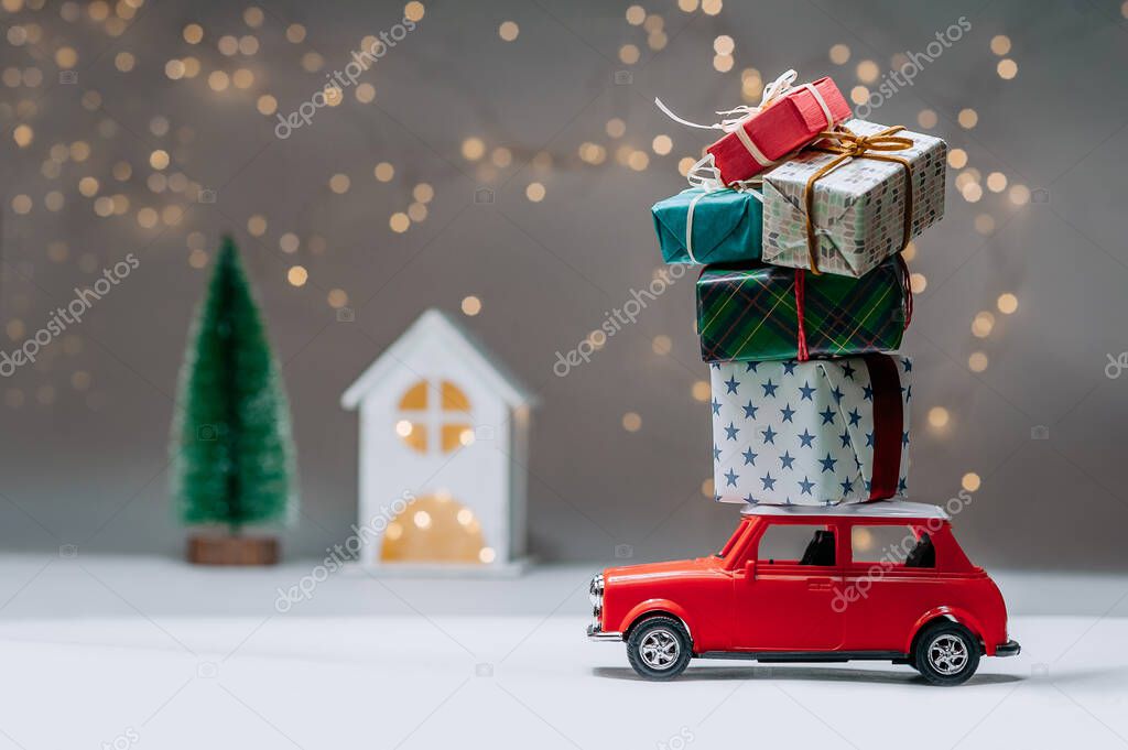 Red car with gifts on the roof. Against the background of the house, and the tree. Concept on the theme of Christmas and New Year