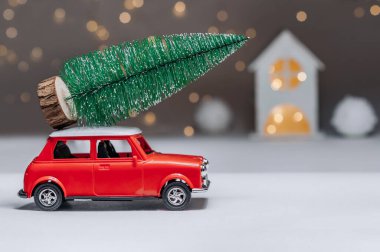 Çatıda Noel ağacı olan kırmızı bir araba. Evin arka planına karşı. Noel ve Yeni Yıl teması kavramı