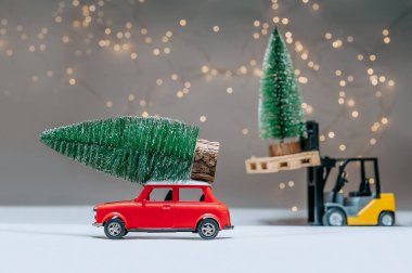 Bir yükleyici ve kırmızı retro manina yeşil ağaçlar taşıyor. Şenlik ışıklarının arka planına karşı. Noel ve Yeni Yıl teması kavramı