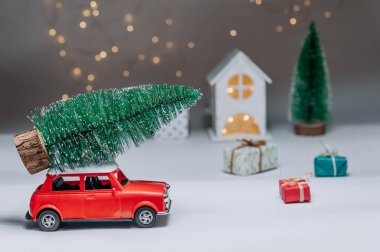 Çatıda Noel ağacı olan kırmızı bir araba. Evin arka planına karşı. Noel ve Yeni Yıl teması kavramı