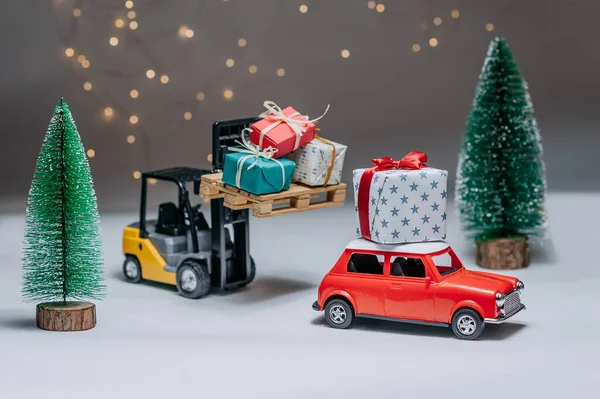 Wózek Widłowy Ładuje Prezenty Czerwonego Samochodu Tle Zielonych Drzew Świątecznych — Zdjęcie stockowe