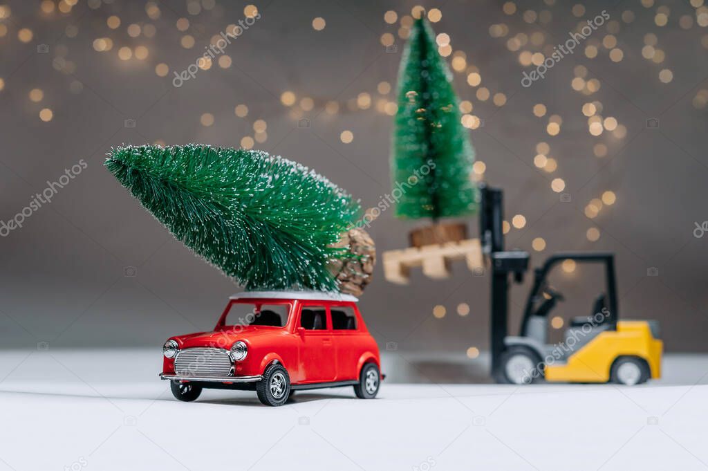 A loader and a red retro manina are carrying green trees. Against the background of festive lights. Concept on the theme of Christmas and New Year