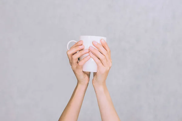 White mug for coffee, tea in the hands of a girl. On a white background