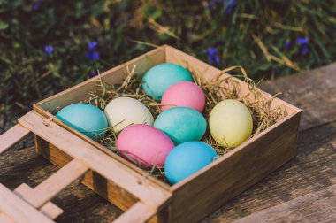 Yakın plan, çiçek arkaplanındaki tahta bir kutuda yumurtalar. Paskalya konsepti