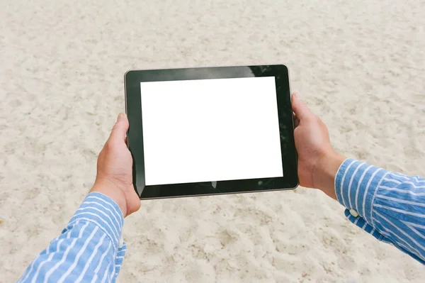 Close up, mock up tablet in the hands of a man. Against the backdrop of the beach and sand