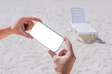 Akıllı telefonları erkeklerin eline bırak. Sahilin ve şezlongların önünde. Rahatlama temasına ilişkin kavram