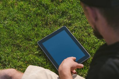 Adam çimenlikteki tablete bakıyor.