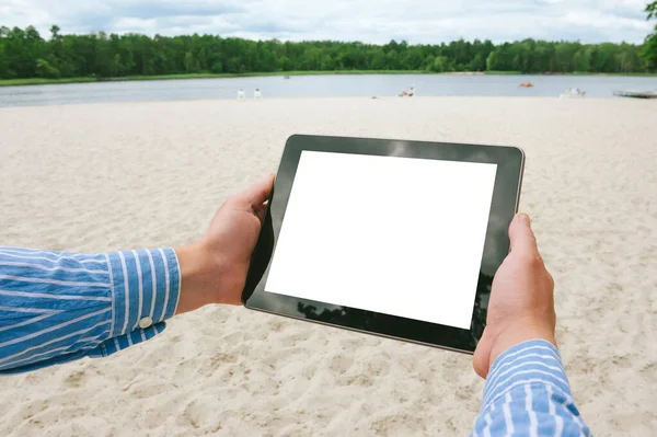 Mock up tablet in the hands of a man. Against the backdrop of the beach and lake