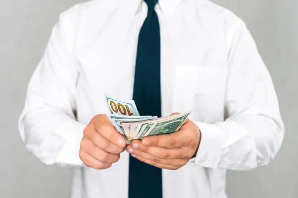 Businessman gives money in a white shirt with a tie. On a light background