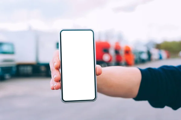 Mock up a smartphone in the hand of a man. Against the background of red trucks. Logistics concept