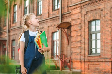 Elinde kitaplarla okul üniforması içindeki genç bir kızın portresi. Eski bir üniversitenin arka planına karşı. Okul konseptine dönelim.