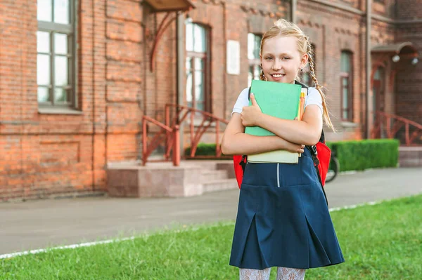 一个穿着校服手里拿着书的小女孩的画像 在一所老大学的背景下 回到学校的概念 — 图库照片