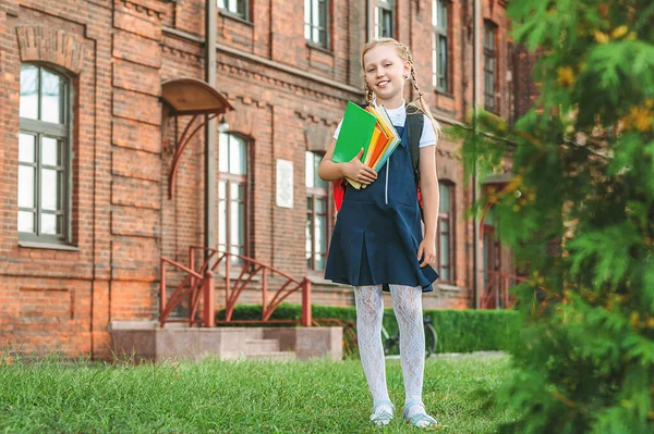 一个穿着校服手里拿着书的小女孩的画像 在一所旧大学的背景下 — 图库照片