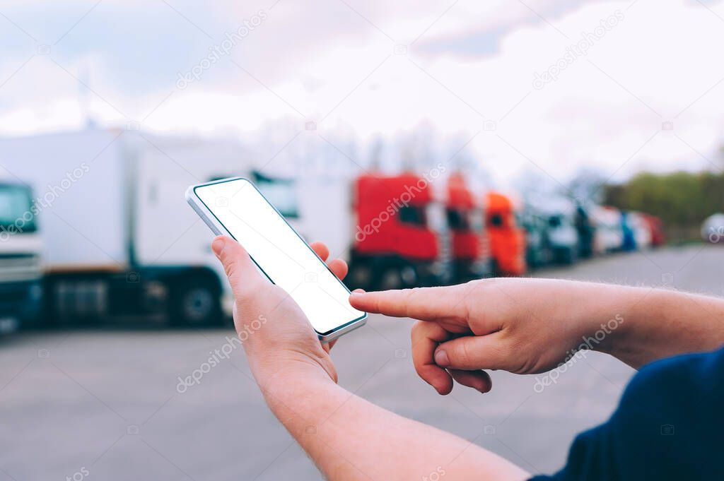 Mock up a smartphone in the hands of a man. Against the background of red trucks. Logistics concept