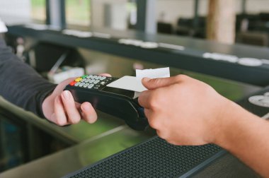 Bir adam terminalden kredi kartıyla ödeme yapıyor.