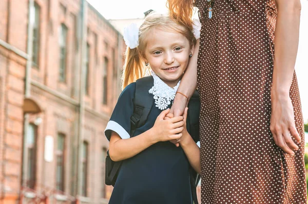 母亲牵着这个小女孩手拉手地走到一年级 回学校去开始上课的时候秋天的第一天 一个女人和一个背着背包的小女孩 — 图库照片