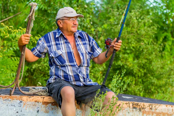 Un uomo anziano con una canna da pesca — Foto Stock