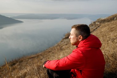Nehrin kenarındaki çimlere bakan bir adamın portresi.