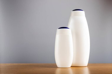 Gri arka planda bir şişe şampuan ve saç kremi. Saç bakımı için Deterjanlar.