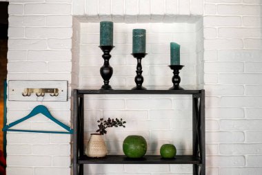 Kafenin duvarında dekoratif askı var. Raflardaki mumlar..