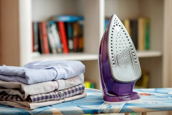 Ütü masasında ütülenmiş gömlek yığınının yanında.