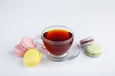 Bir fincan çay ve beyaz arka planda renkli kurabiyeler..