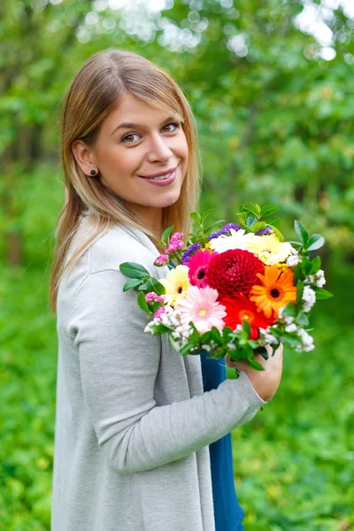 Gelukkig meisje met een boeket bloemen — Stockfoto