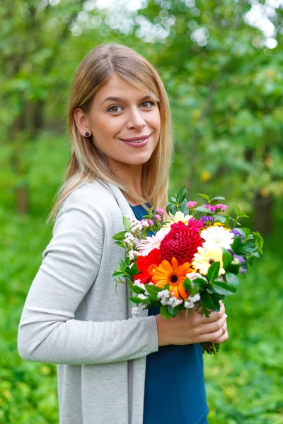 Jonge lachende vrouw met een boeket van bloemen — Stockfoto
