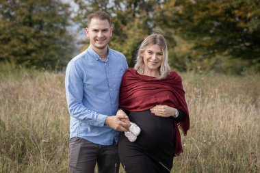 Doğumu bekleyen mutlu çift dışarıda hatıralar yaratıyor. Hamilelik fotoğrafı çekimi.