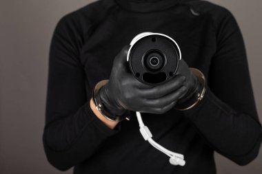 Gri arkaplandaki güvenlik kameralarını kapatan hırsızların ellerinin resmini kapat