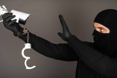 Siyah maskeli bir hırsızın fotoğrafı güvenlik kamerasını kapatmaya çalışıyor.