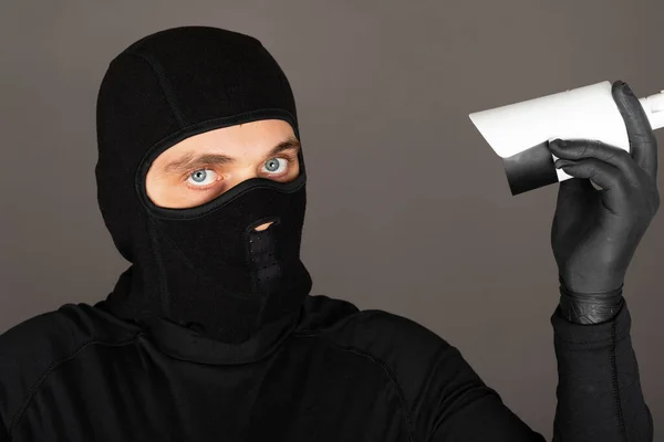 黒い顔のマスクをした泥棒の写真は 監視カメラをオフにしようとしています — ストック写真