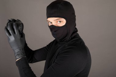 Siyah kostüm giymiş ve maske takmış bir hırsızın güvenlik kamerasını kapatmaya çalışırken çekilmiş fotoğrafı.