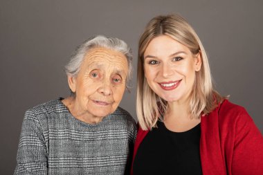 Kameraya gülümseyen sevimli büyükannesi olan güzel sarışın bir kadının stüdyo portresi.