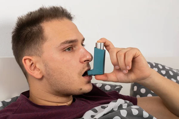 季節性インフルエンザの若い男性患者はサルブタモールと吸入器を使用しています — ストック写真