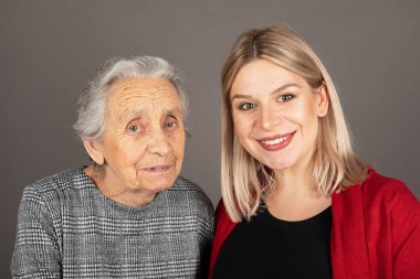 Kameraya gülümseyen sevimli büyükannesi olan güzel sarışın bir kadının stüdyo portresi.