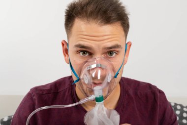 Nefes almak için oksijen maskesi takan beyaz bir adamın portresi.