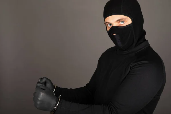 Siyah Maskeli Üniformalı Bir Gencin Resmi Gri Arka Planda Kelepçeli — Stok fotoğraf