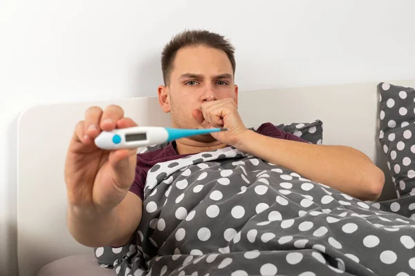 Sick Young Caucasian Man Lying Bed Home Holding Digital Thermometer — Stock Photo, Image