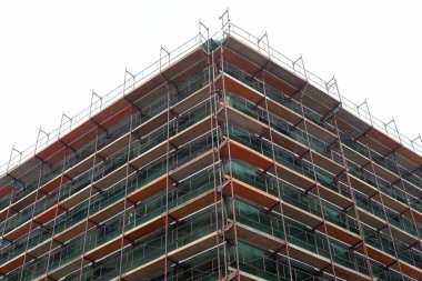 Bir inşaat sahasının resmi, gökyüzüne karşı gelişmekte olan modern düz bina.