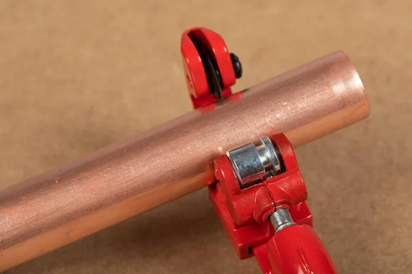 Cutting a copper pipe with a red pipe cutter