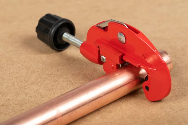 Cutting a copper pipe with a red pipe cutter