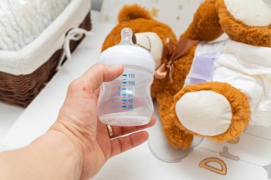 Bebek yatağında bebek bezi takmış kahverengi bir ayı heykeli.